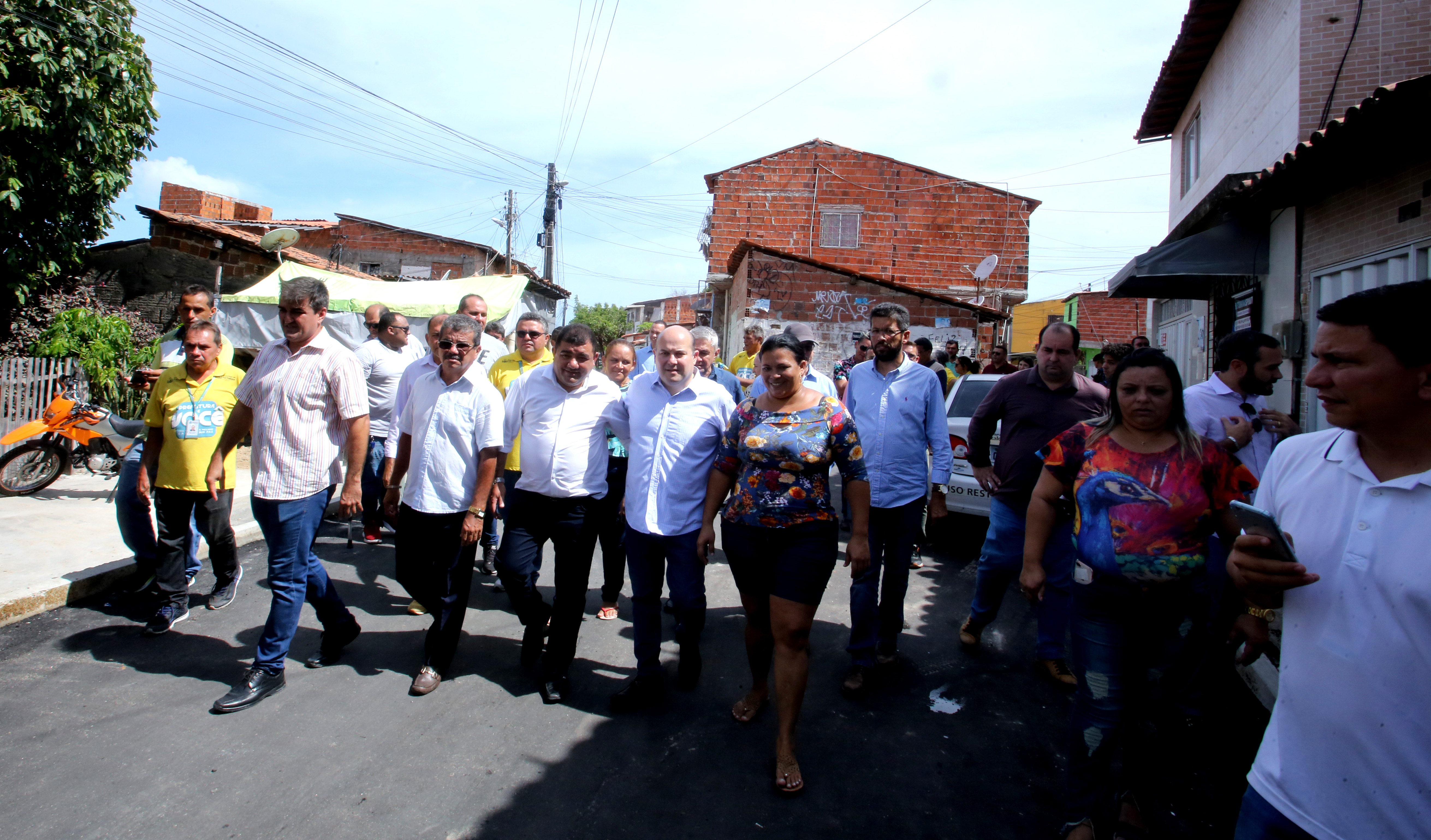 várias pessoas caminham por uma rua asfaltada